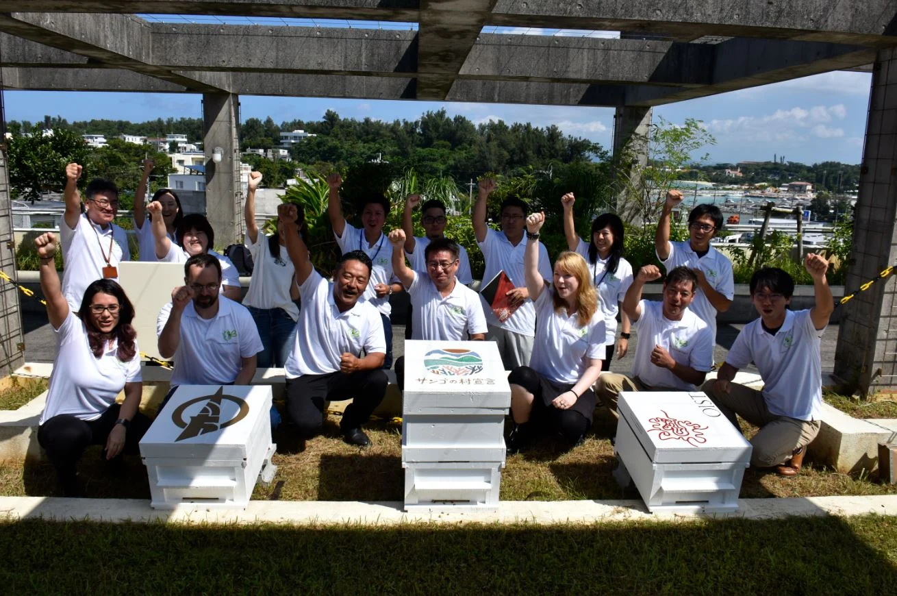 Maéva Techer and collaborators gathered with decorated honey bee hives during a scientific event in Okinawa.