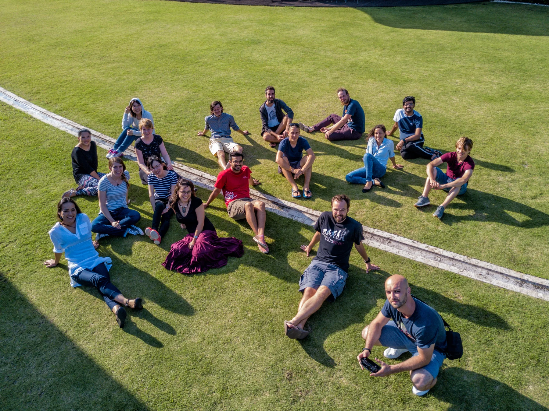 Maéva Techer and colleagues seated on a lawn at OIST in Okinawa, photographed from above.
