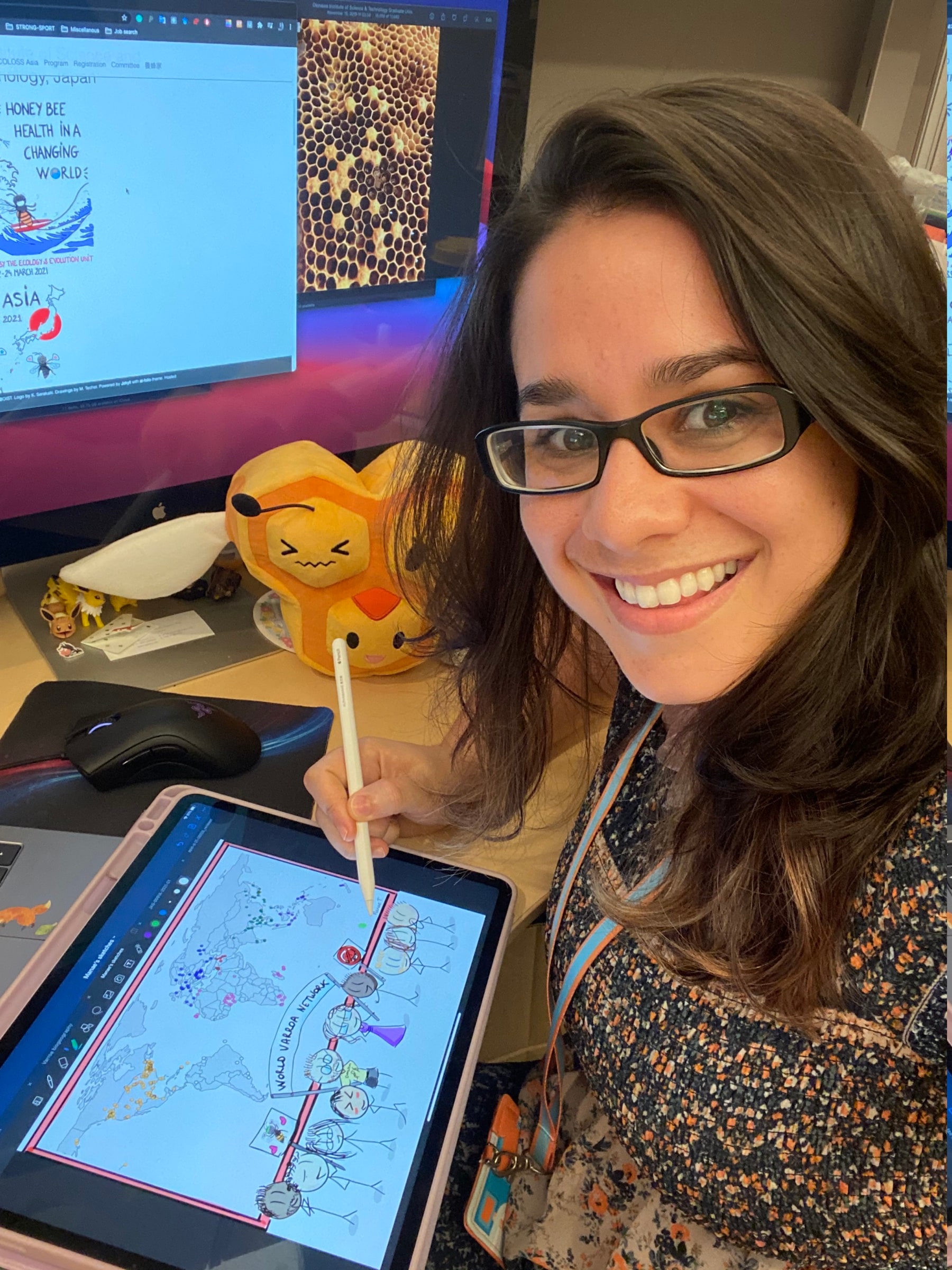 Maéva Techer drawing the World Varroa Network illustration on a tablet beside honey bee research material.